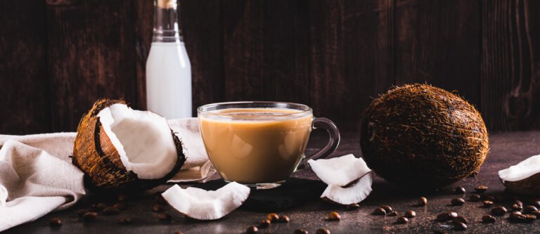 Vietnamese coconut coffee in a cup and coconut pieces on the table web banner
