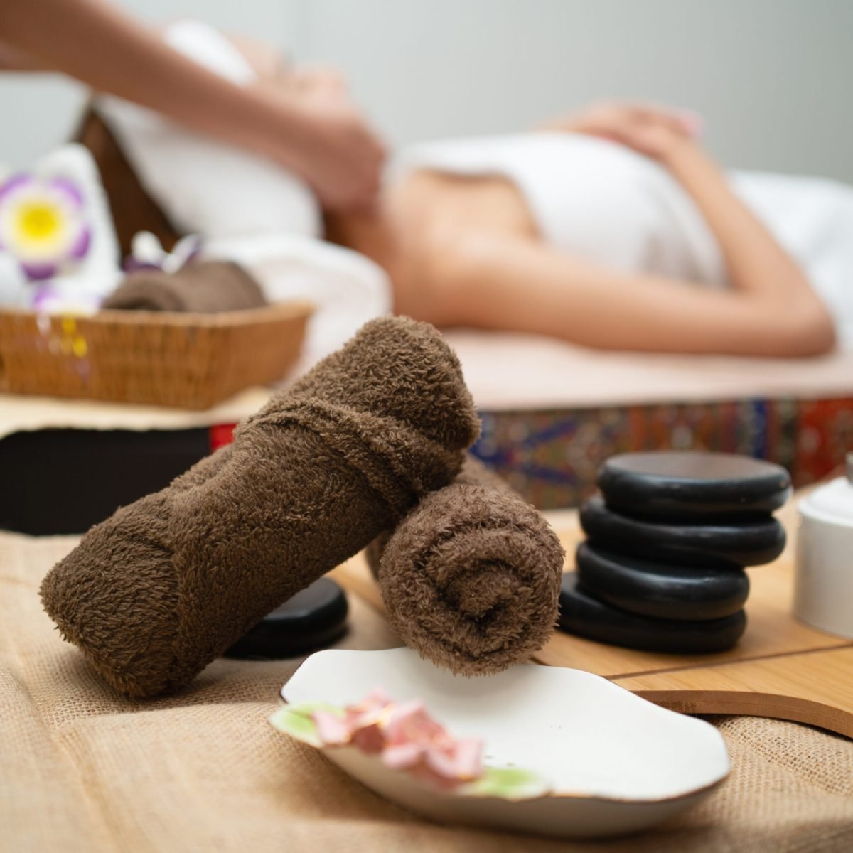 woman is getting a facial treatment with a basket of towels and a tray of stones